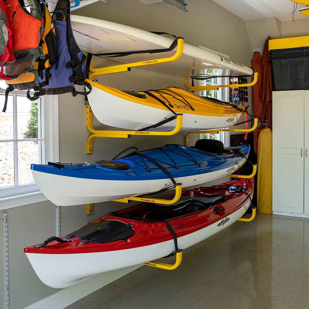 Kayaks stacked on a suspenz flat rack inside a garage.