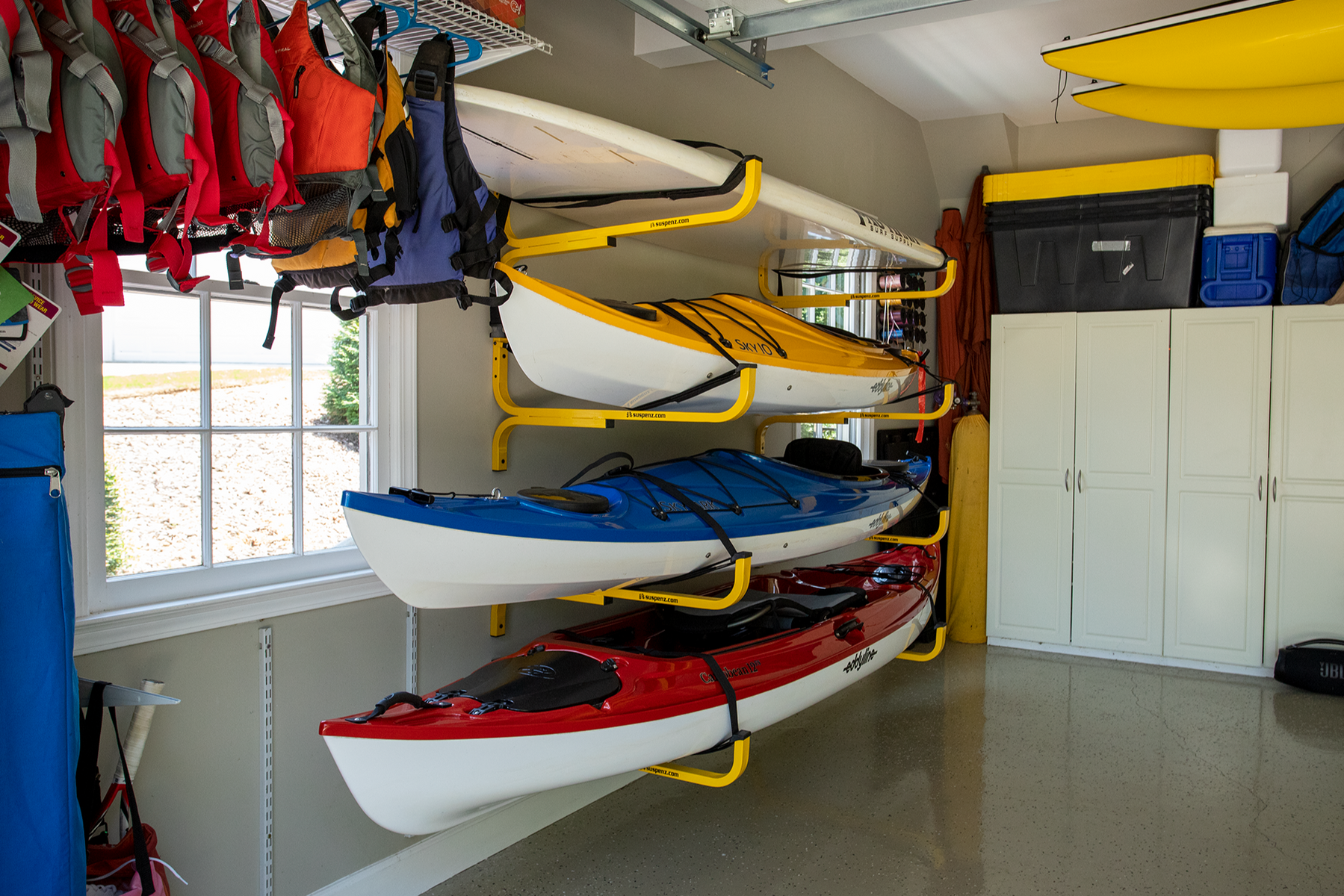 Garage with kayak storage system, life vests, and cabinets.