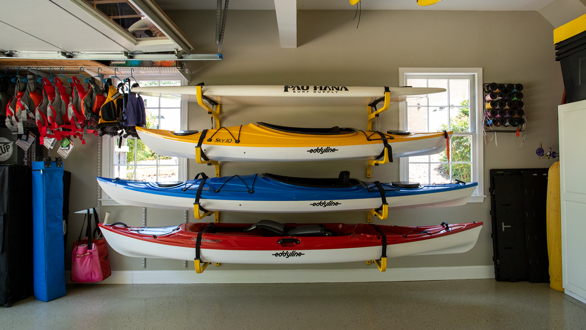 Stack of kayaks on a rack in a garage with various items around