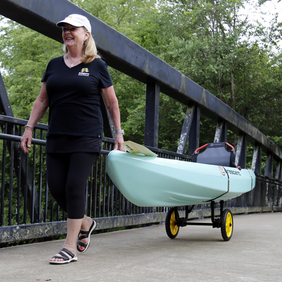 Woman pulling a kayak on the Catch-All Universal Airless Cart