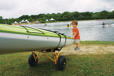 A small child pushing the Kayak and Canoe Transportation Cart