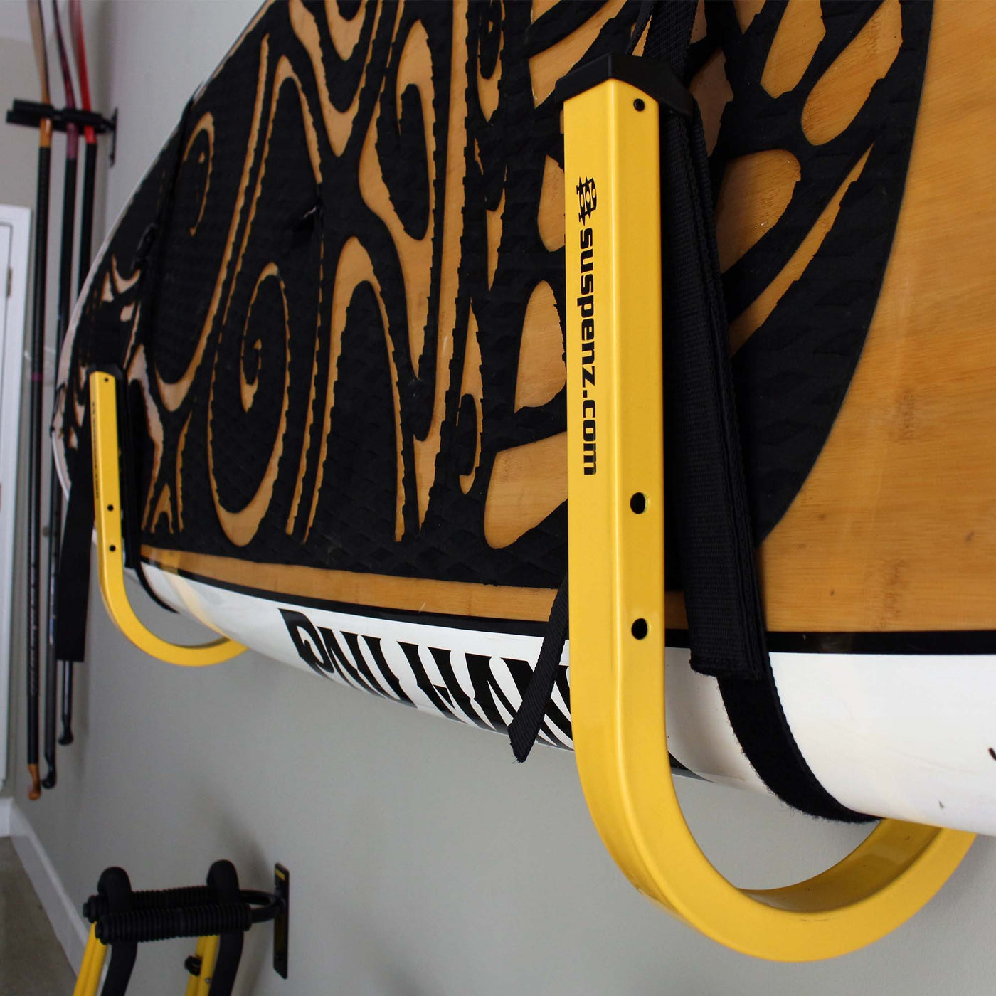 1 set of stand-up paddleboard wall storage mounted to a garage wall with a SUP loaded on it.