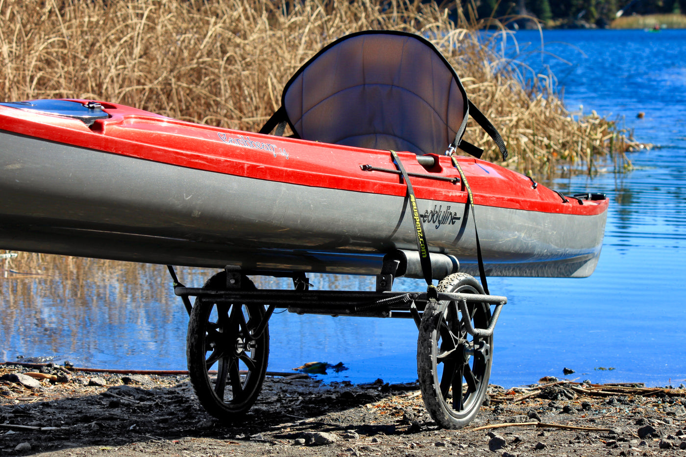 Kayak strapped on the all-terrain cart near a lake.