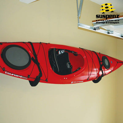 A red kayak resting on an ez rack mounted to a garage wall